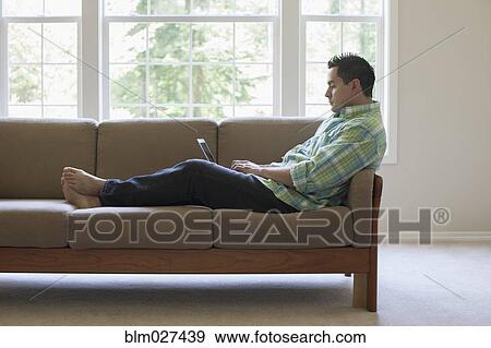Pacific Islander man using laptop on sofa View Large Photo Image Stock Photo - Pacific Islander man using laptop on sofa. Fotosearch