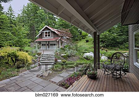 Stock Photo - Rocking chair on porch overlooking garden. Fotosearch