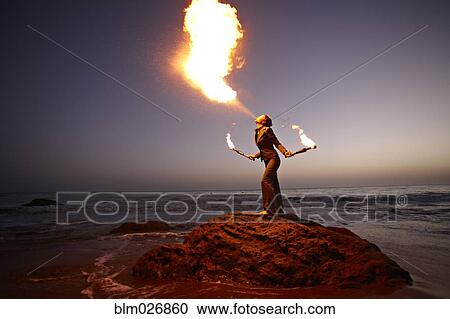 Woman breathing fire on rocky beach View Large Photo Image Stock Image - Woman breathing fire on rocky beach. Fotosearch