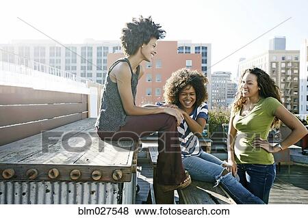Stock Photo - Women relaxing on urban rooftop. Fotosearch