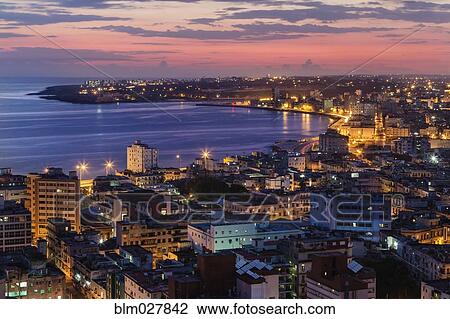 Stock Image - Aerial view of city skyline lit up at sunrise, Havana, Cuba. Fotosearch