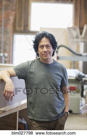 Stock Photo - Asian carpenter smiling in workshop. Fotosearch