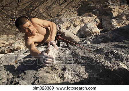 Asian climber scaling steep cliff face View Large Photo Image Stock Photo - Asian climber scaling steep cliff face. Fotosearch
