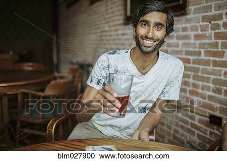 Stock Image - Asian man drinking beer in pub. Fotosearch
