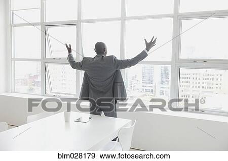 Black businessman cheering in office View Large Photo Image Stock Photo - Black businessman cheering in office. Fotosearch