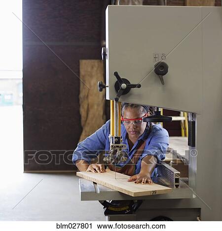 Stock Image - Black carpenter cutting wood in workshop. Fotosearch