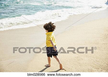 Stock Photograph - Boy walking on beach. Fotosearch