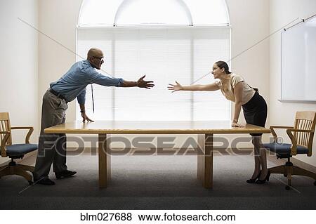 Stock Photo - Business people shaking hands across table. Fotosearch