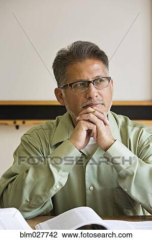 Stock Image - Businessman sitting at desk in office. Fotosearch