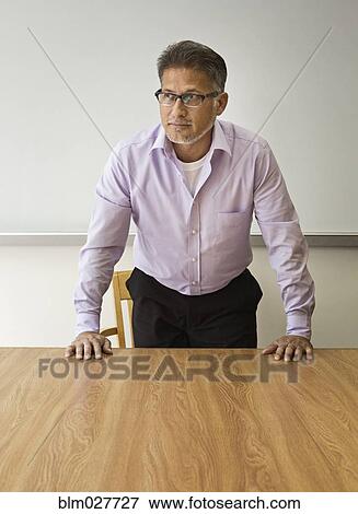 Stock Photo - Businessman standing at table in conference room. Fotosearch