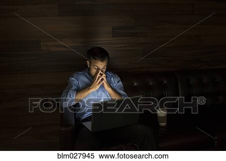 Businessman using laptop on sofa at night View Large Photo Image Stock Photography - Businessman using laptop on sofa at night. Fotosearch