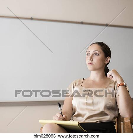 Stock Image - Businesswoman making notes in office. Fotosearch