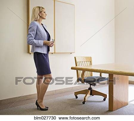 Businesswoman standing at table in conference room View Large Photo Image Stock Image - Businesswoman standing at table in conference room. Fotosearch