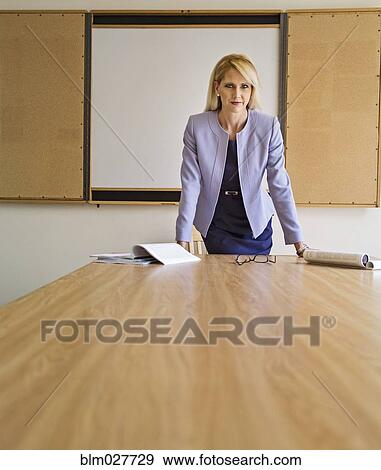 Stock Photo - Businesswoman standing at table in conference room. Fotosearch