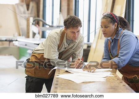 Carpenters looking at plans in workshop View Large Photo Image Stock Photo - Carpenters looking at plans in workshop. Fotosearch