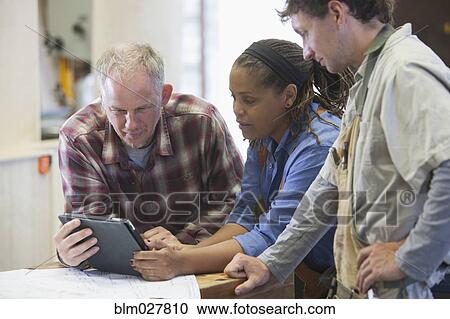 Stock Image - Carpenters using digital tablet in workshop. Fotosearch