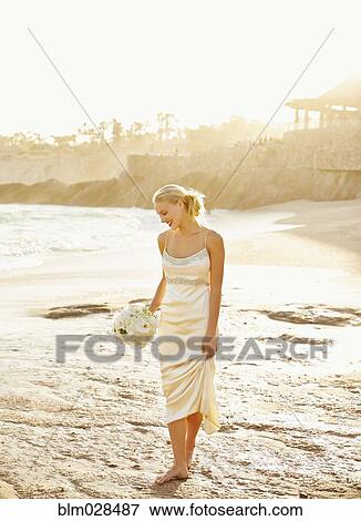 Caucasian bride holding bouquet on beach View Large Photo Image Stock Photo - Caucasian bride holding bouquet on beach. Fotosearch