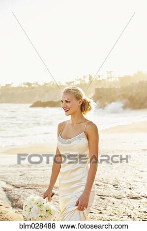 Caucasian bride holding bouquet on beach View Large Photo Image Stock Photo - Caucasian bride holding bouquet on beach. Fotosearch