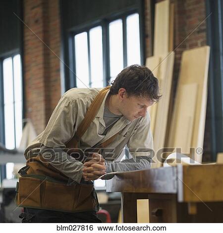 Caucasian carpenter reviewing blueprint in workshop View Large Photo Image Stock Photograph - Caucasian carpenter reviewing blueprint in workshop. Fotosearch