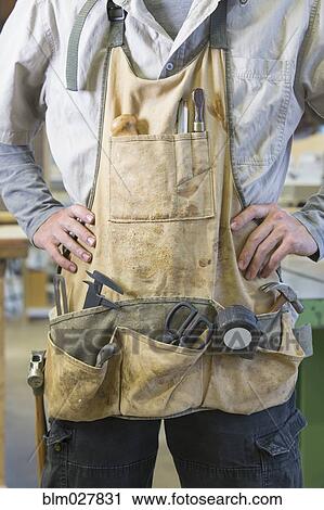 Stock Image - Caucasian carpenter wearing apron. Fotosearch