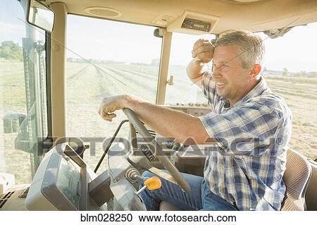Stock Image - Caucasian farmer driving tractor. Fotosearch