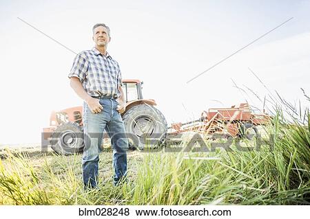 Stock Photo - Caucasian farmer standing in field. Fotosearch