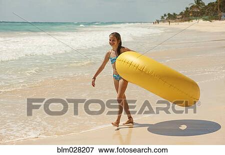 Caucasian girl carrying inflatable ring on beach View Large Photo Image Stock Photo - Caucasian girl carrying inflatable ring on beach. Fotosearch