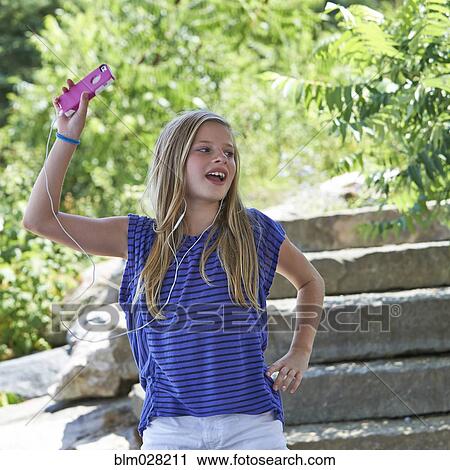 Stock Image - Caucasian girl listening to mp3 player outdoors. Fotosearch