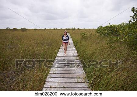 Caucasian girl on wooden walkway in rural landscape View Large Photo Image Stock Image - Caucasian girl on wooden walkway in rural landscape. Fotosearch
