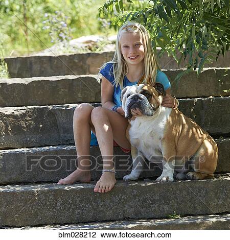 Stock Image - Caucasian girl petting dog on steps outdoors. Fotosearch