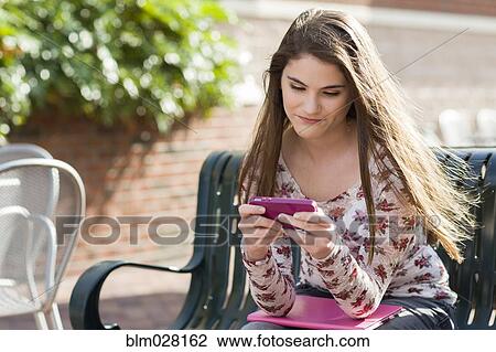 Stock Image - Caucasian girl using cell phone outdoors. Fotosearch