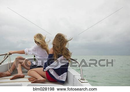 Stock Photo - Caucasian girls sitting on boat. Fotosearch