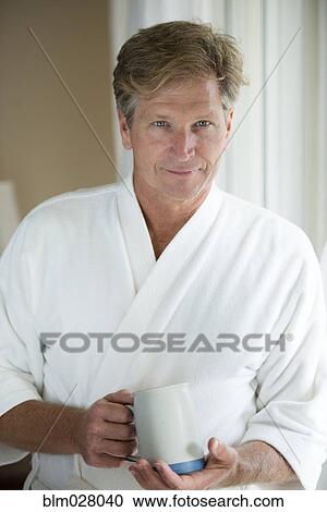 Stock Image - Caucasian man having coffee in bathrobe. Fotosearch
