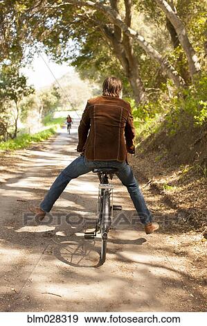Caucasian man riding bicycle on rural road View Large Photo Image Stock Photo - Caucasian man riding bicycle on rural road. Fotosearch