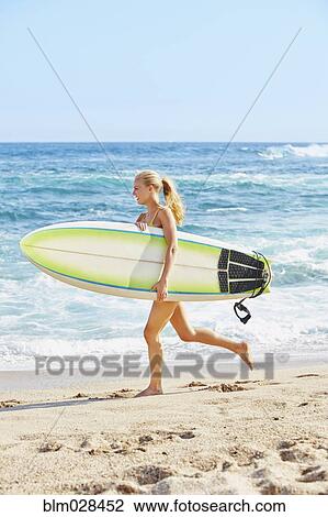 Caucasian woman carrying surfboard on beach View Large Photo Image Stock Image - Caucasian woman carrying surfboard on beach. Fotosearch