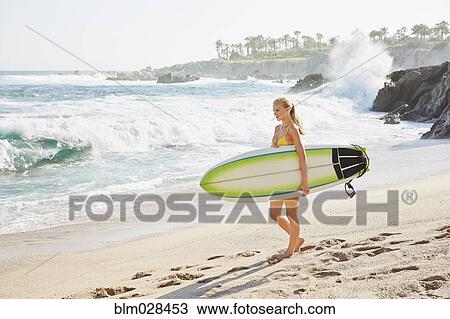 Caucasian woman carrying surfboard on beach View Large Photo Image Stock Image - Caucasian woman carrying surfboard on beach. Fotosearch