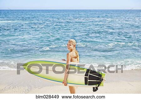 Caucasian woman carrying surfboard on beach View Large Photo Image Stock Photo - Caucasian woman carrying surfboard on beach. Fotosearch