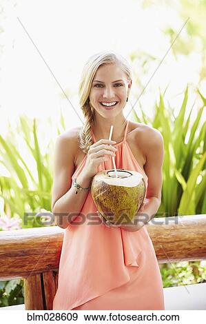 Stock Photo - Caucasian woman drinking from coconut. Fotosearch