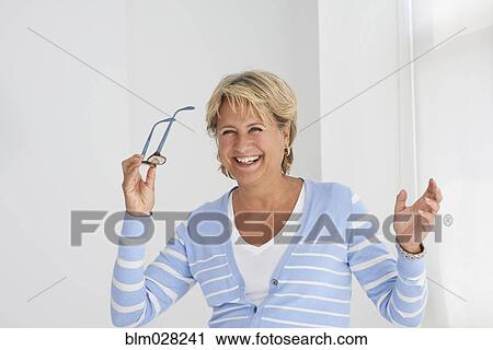 Stock Image - Caucasian woman holding eyeglasses. Fotosearch
