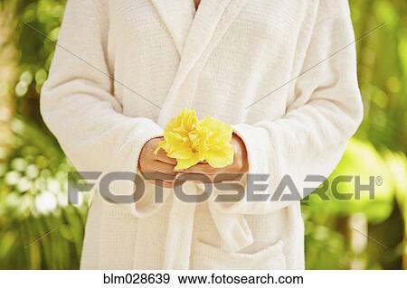 Stock Photo - Caucasian woman in bathrobe holding flower. Fotosearch