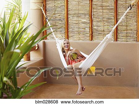 Caucasian woman in hammock drinking from coconut View Large Photo Image Stock Photo - Caucasian woman in hammock drinking from coconut. Fotosearch