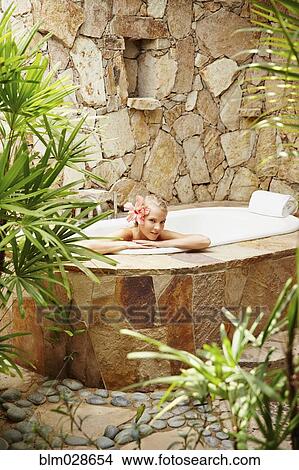 Picture - Caucasian woman relaxing in outdoor soaking tub. Fotosearch