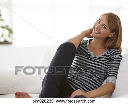 Stock Image - Caucasian woman relaxing on sofa. Fotosearch