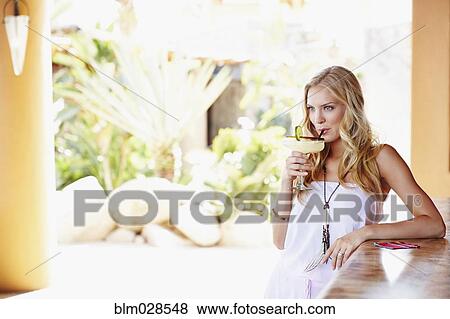 Stock Photo - Caucasian woman sipping margarita in bar. Fotosearch