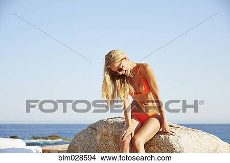 Caucasian woman sitting on rock on beach View Large Photo Image Picture - Caucasian woman sitting on rock on beach. Fotosearch