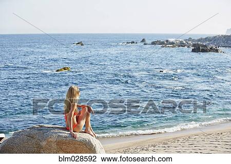 Caucasian woman sitting on rock on beach View Large Photo Image Stock Image - Caucasian woman sitting on rock on beach. Fotosearch