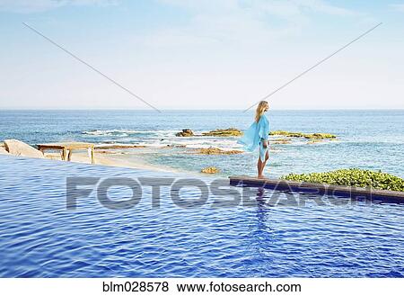 Caucasian woman standing at the edge of infinity pool View Large Photo Image Stock Photo - Caucasian woman standing at the edge of infinity pool. Fotosearch