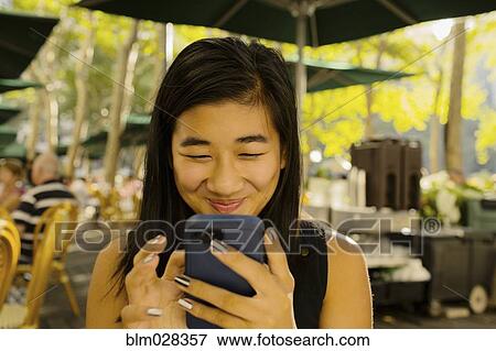 Chinese girl using cell phone on restaurant patio View Large Photo Image Stock Photo - Chinese girl using cell phone on restaurant patio. Fotosearch