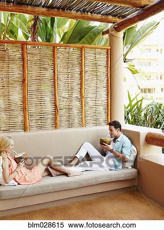 Couple drinking from coconuts on patio sofa View Large Photo Image Stock Photography - Couple drinking from coconuts on patio sofa. Fotosearch
