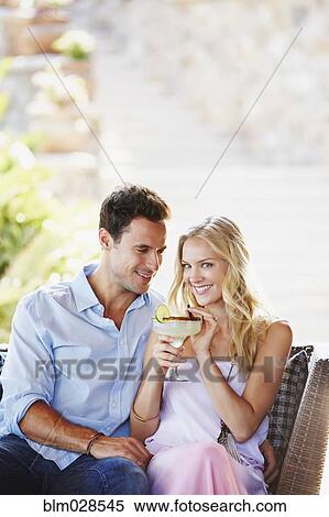 Stock Photography - Couple having margarita together on sofa. Fotosearch